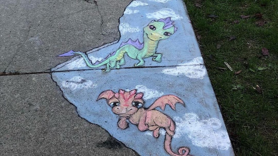 Chalk drawing on a sidewalk showing dragons in the sky.