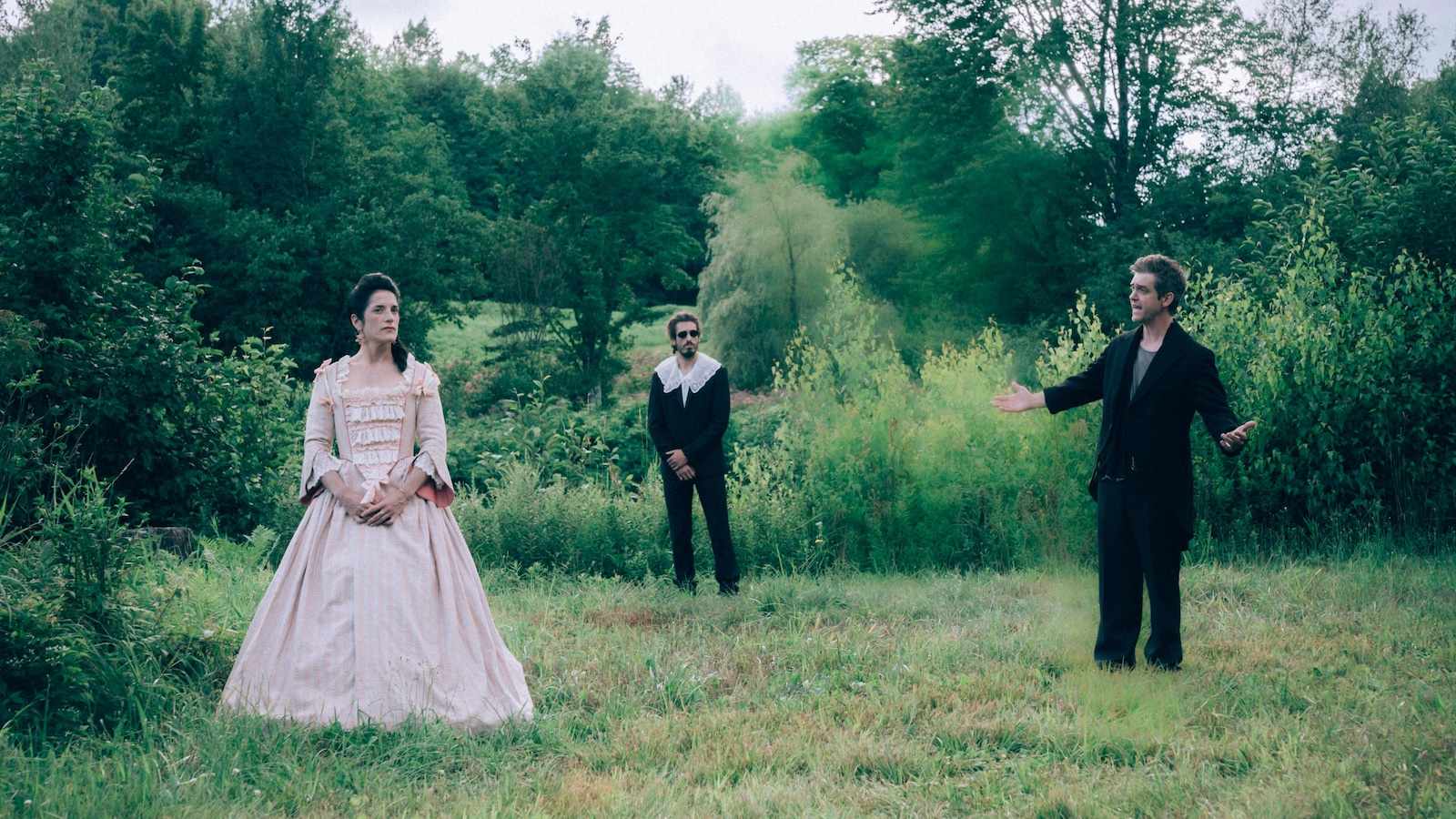 In a field, two men and a woman (Eve Dorso) in old dress.