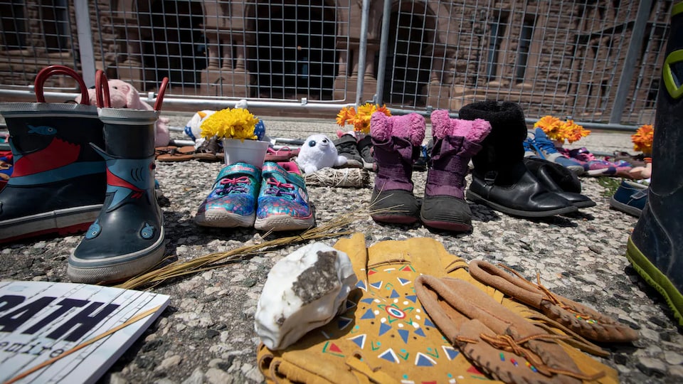 Children's shoes and other items left in Queen's Park in memory of students who died at Kamloops Residential School.