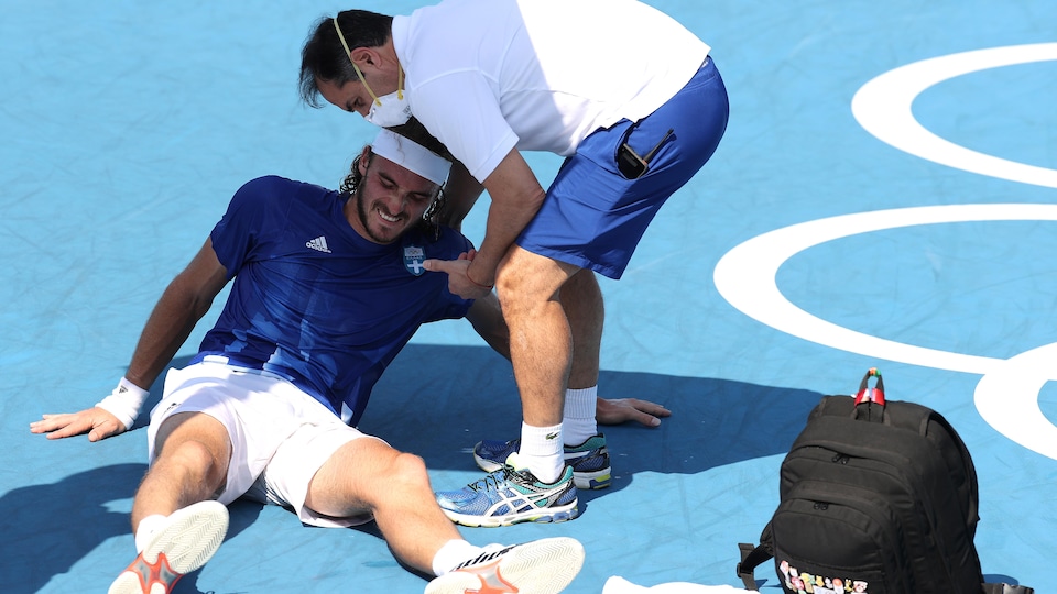Stefanos Tsitsipas receives treatment from a therapist in the field.