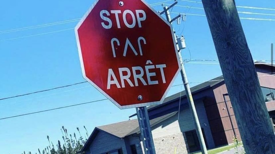 Stop sign translated into English and cry on the side of the road.