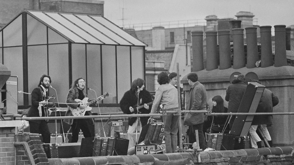 The Beatles perform on the roof of a building in London. 