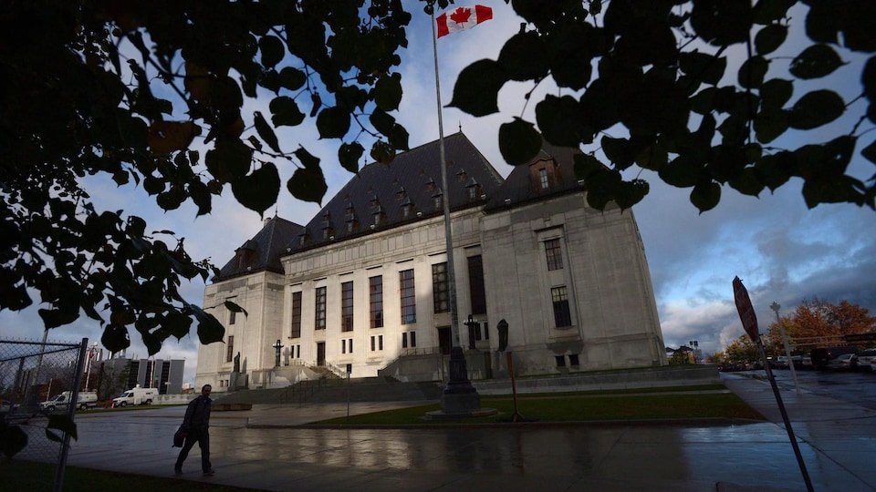 A man walks in front of the Supreme Court of Canada.