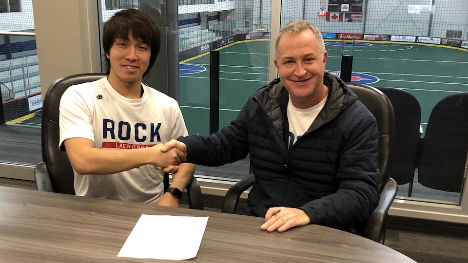 Koichi Nakamura shaking hands with rock music owner Jimmy Dawik.