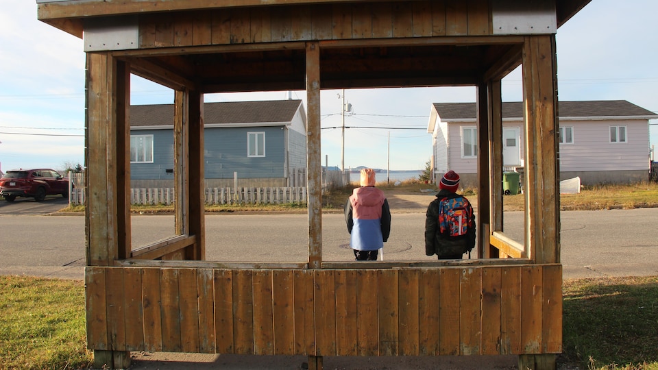 Two children waiting at a bus shelter.