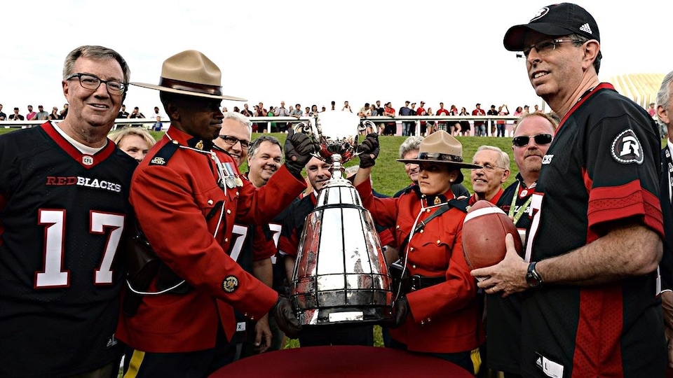 Ottawa Mayor Jim Watson (left) and former Ottawa Rough Riders player Tony Gabriel (right) with the gray trophy. 