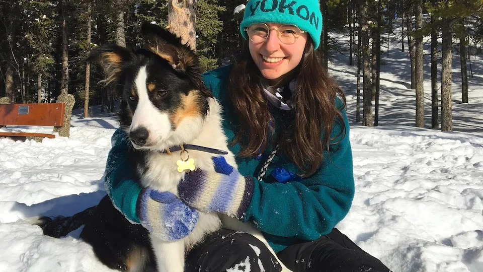 Young woman and her dog in the Yukon Forest.