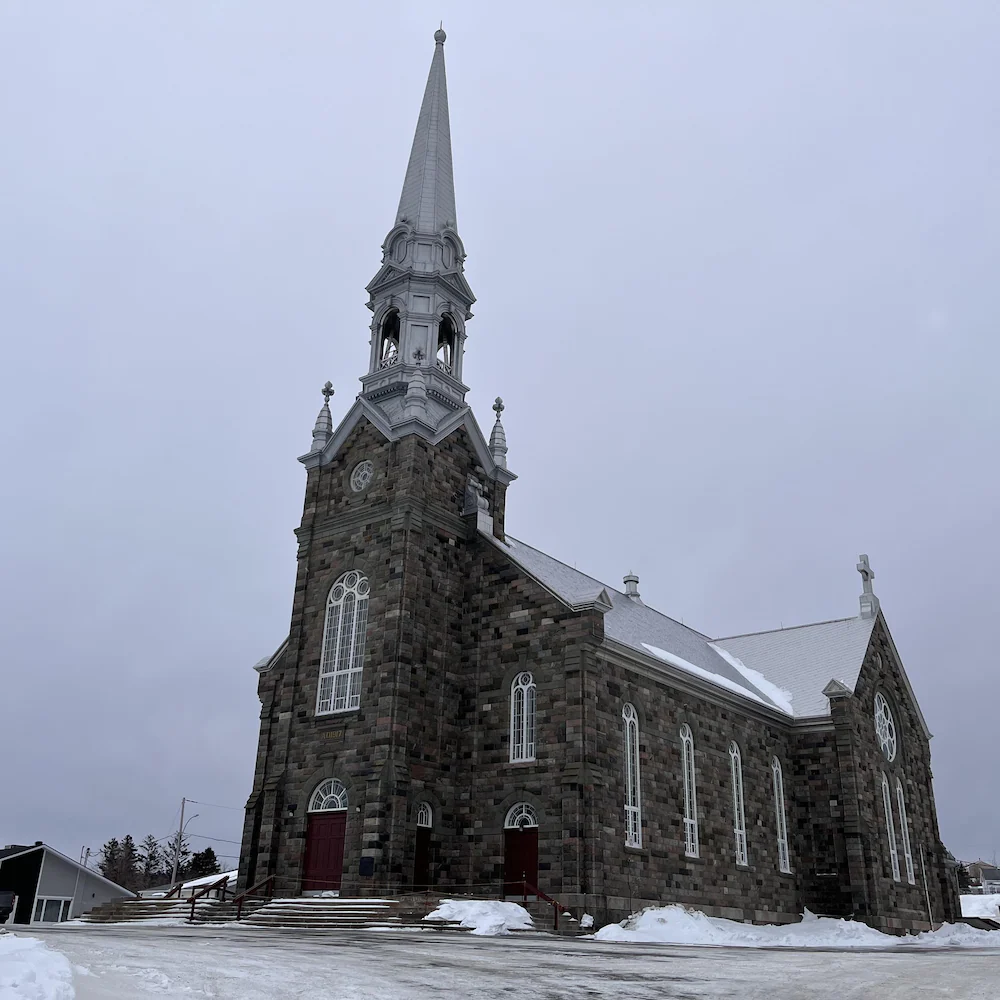 The Cap-Chat Church is seen from the outside under a very gray sky.