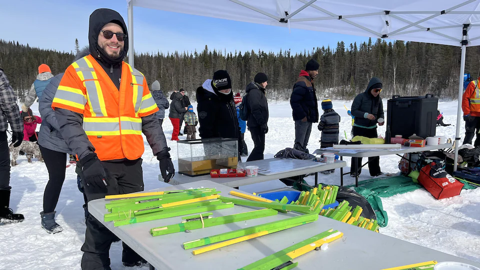 A volunteer stands by a table with ice fishing gear.
