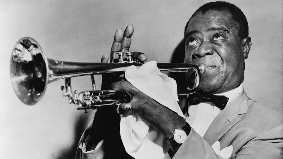 A man plays the trumpet in a black and white photo. 