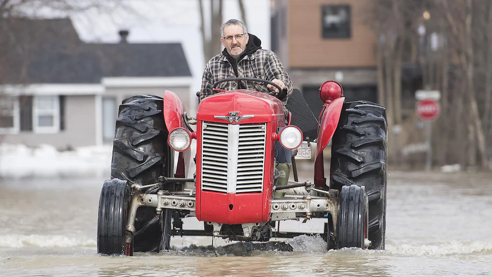 A man drives a tractor on a flooded street