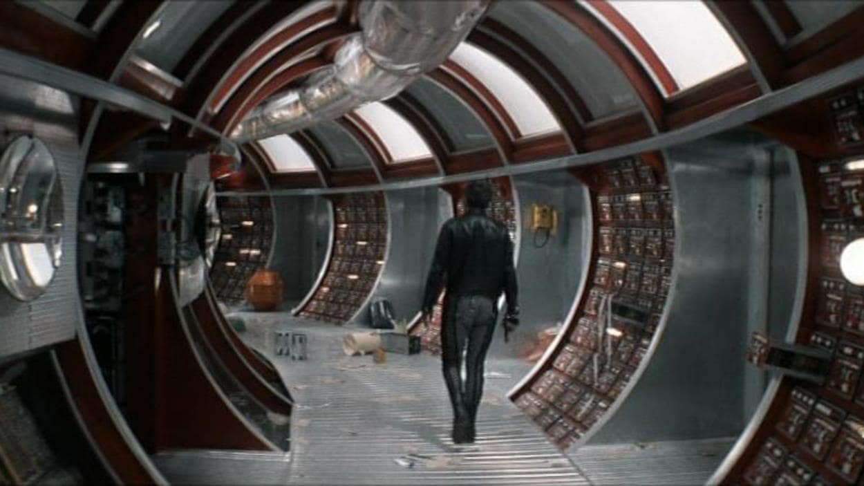 A man from behind in a space station's circular corridor.