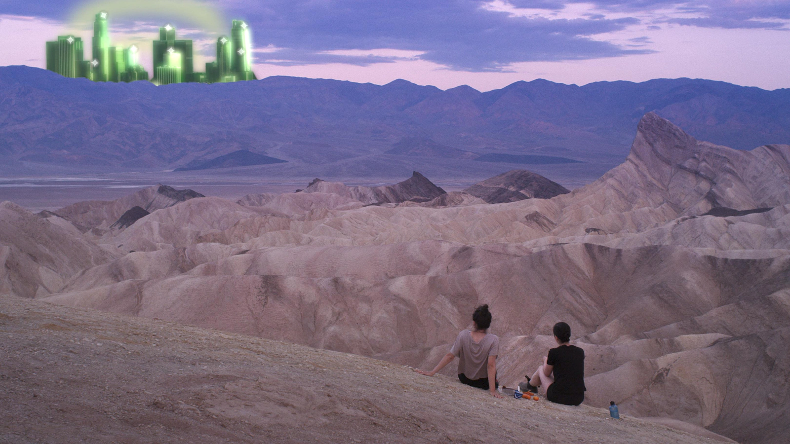Two little girls sitting in the desert facing a green virtual city scene.