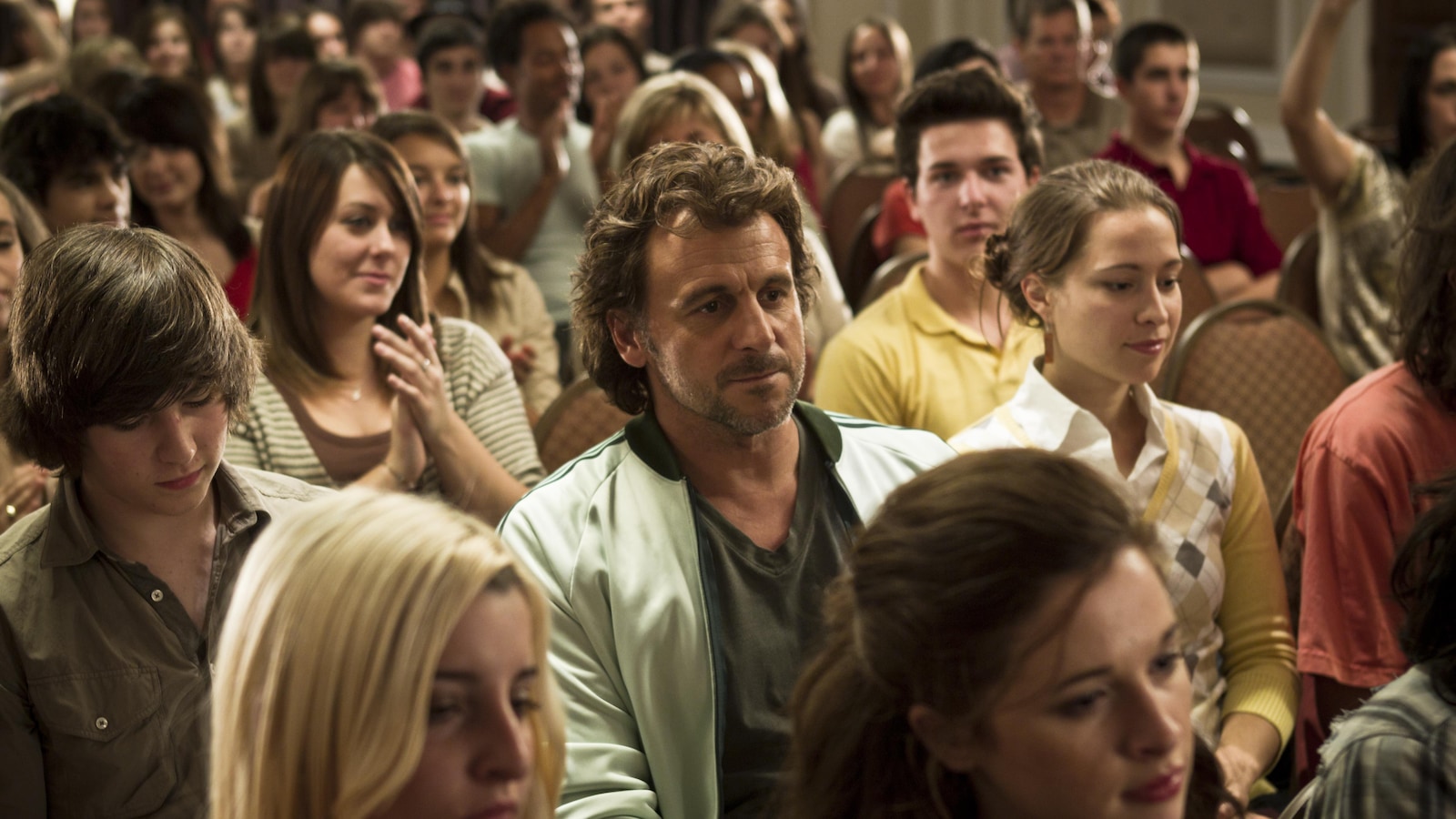 Patrick Howard plays Starbuck, sitting in the middle of a crowd