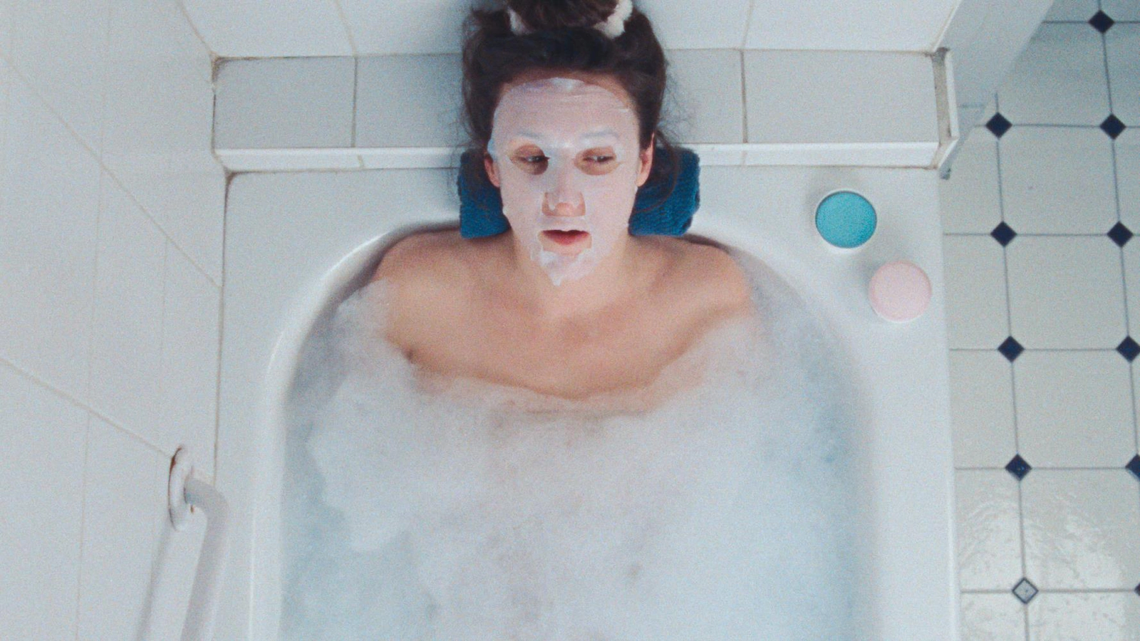 A woman (Anne-Élisabeth Bossé) in a bath, a mask on her face.