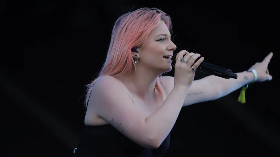 The singer sings and points with her left hand. 
