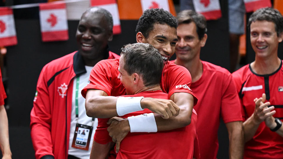 A tennis player hugs another player after his victory.